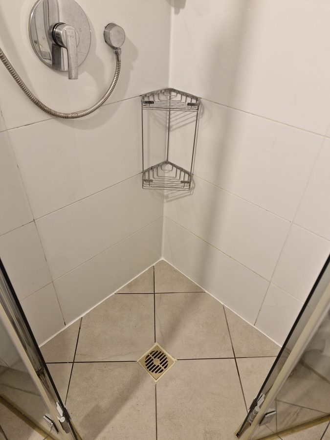 מקלחון אחרי העבודה: פס סיליקון לבן נקי לאורך המפגש בין הקירות לרצפה ומחסום עם רשת חדשה